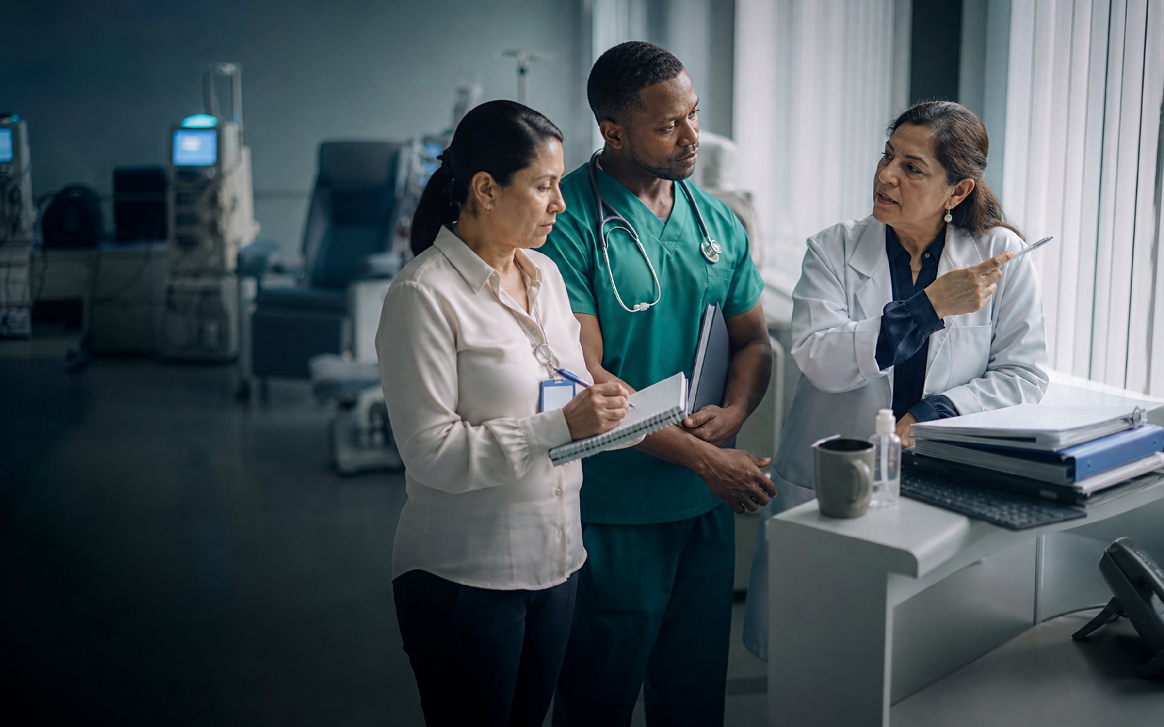 Equipo de una unidad de hemodiálisis —médico, enfermería y administración— revisando juntos la agenda del turno